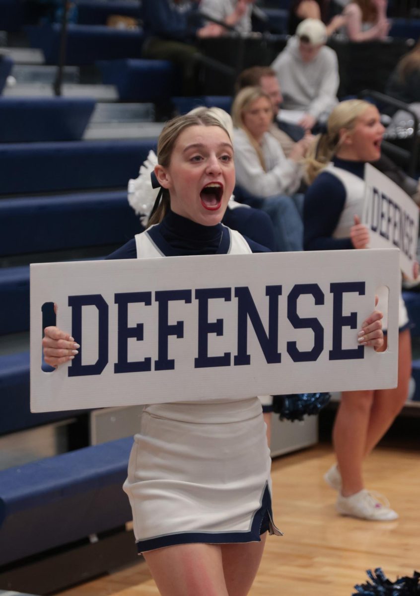 Holding a sign, junior Bella McPeake yells defense at the crowd.
