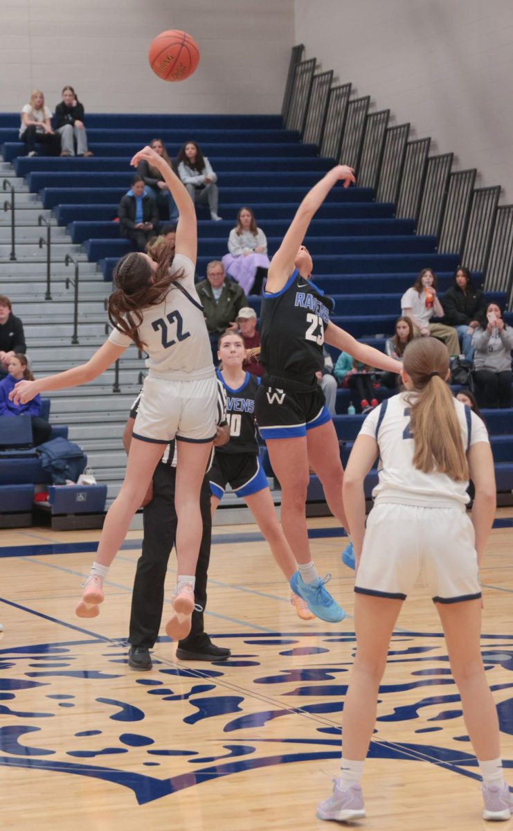 Jumping up, junior Paige Roth smacks the ball to her teammate at tipoff.
