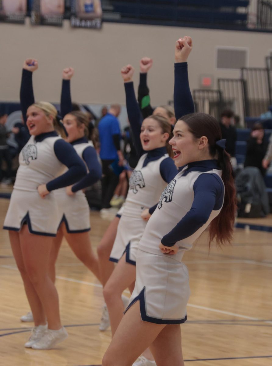 Smiling, senior Trinity Wilson cheers to motivate the people in the stands.
