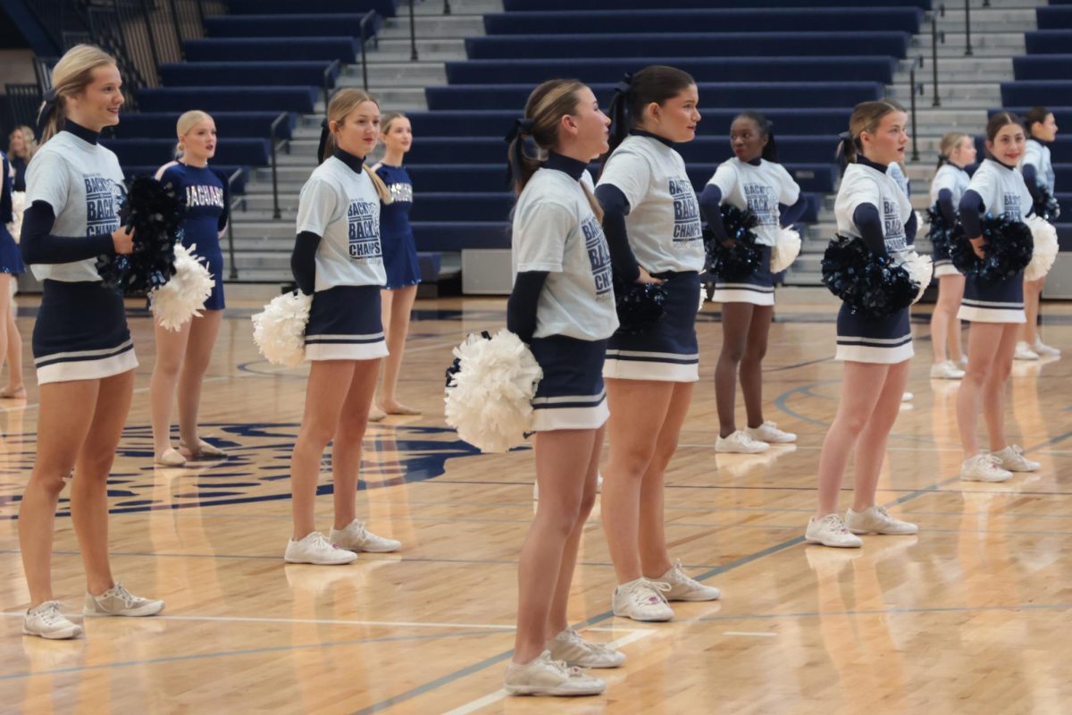 The cheer team stands in uniform, preparing to do their assembly routine.