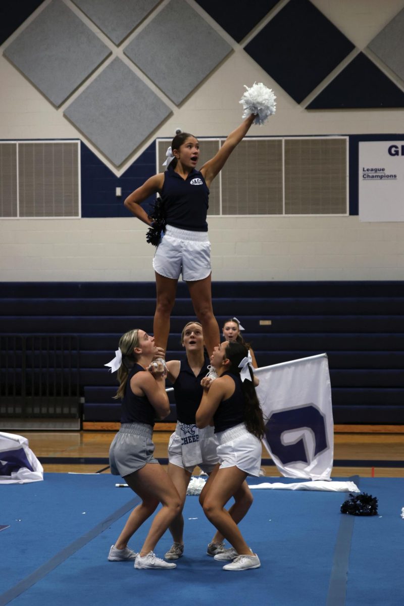 Senior Emersyn Jones holds one pom pom up while being lifted into the air on Jan. 13