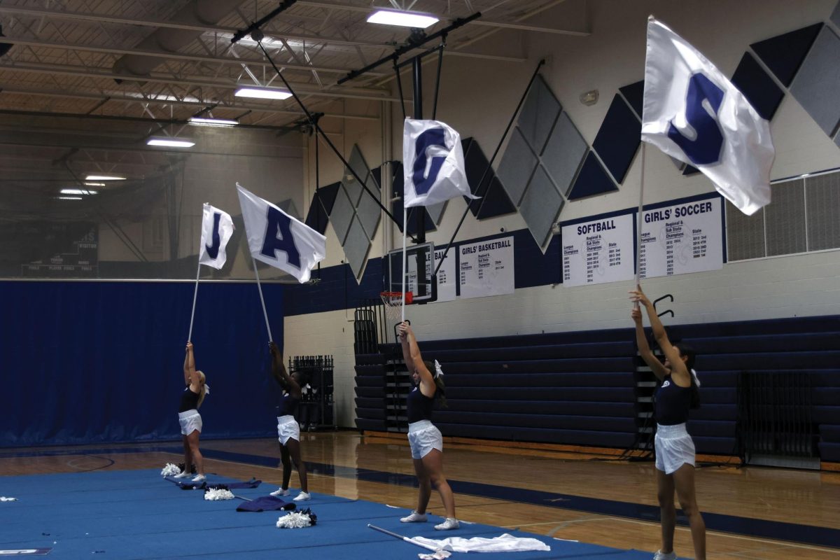 Four cheerleaders wave their flags in unison during the Fight Song on Jan. 13