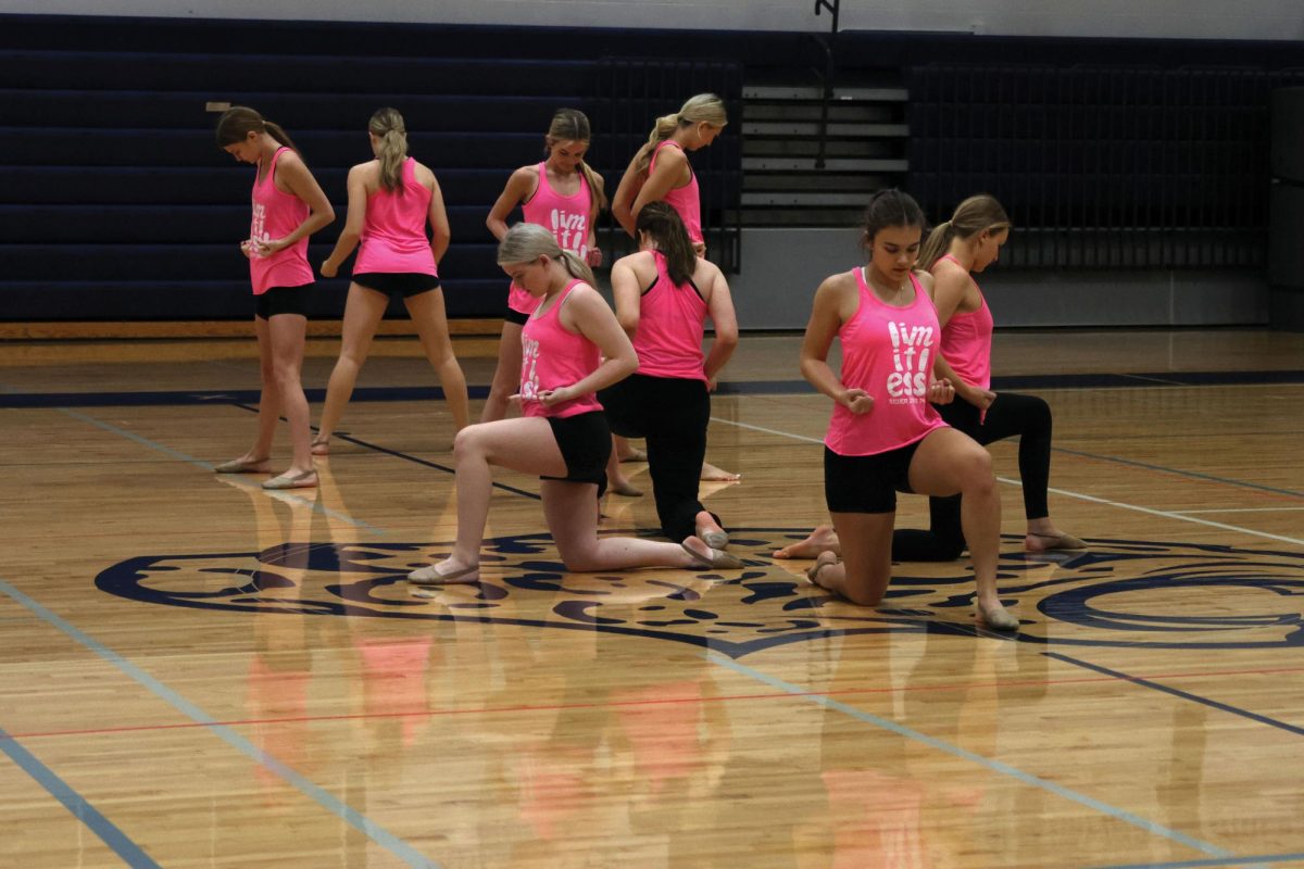 Senior Josie Mason kneels in the front of the group with her face pointing towards the ground, waiting for the music to start on Jan. 13.