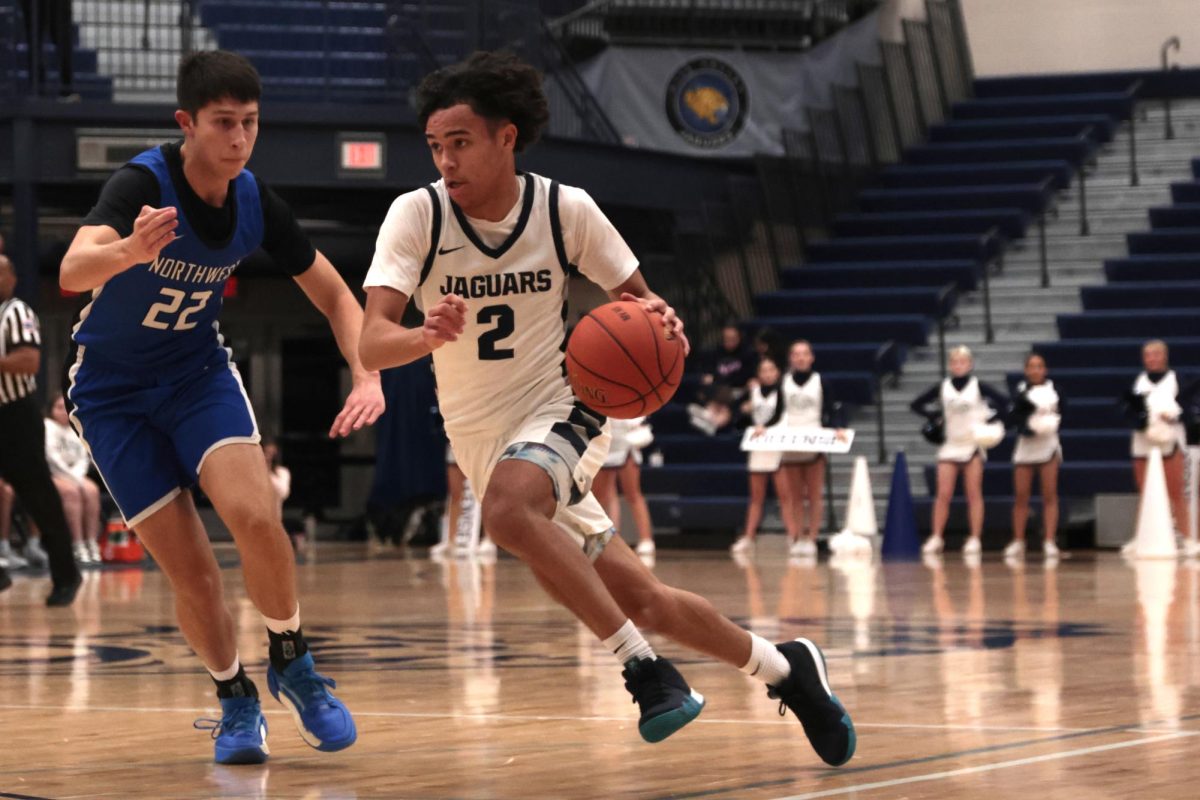 Looking for an open teammate, junior JaKhai Carter dribbles the ball down the court.