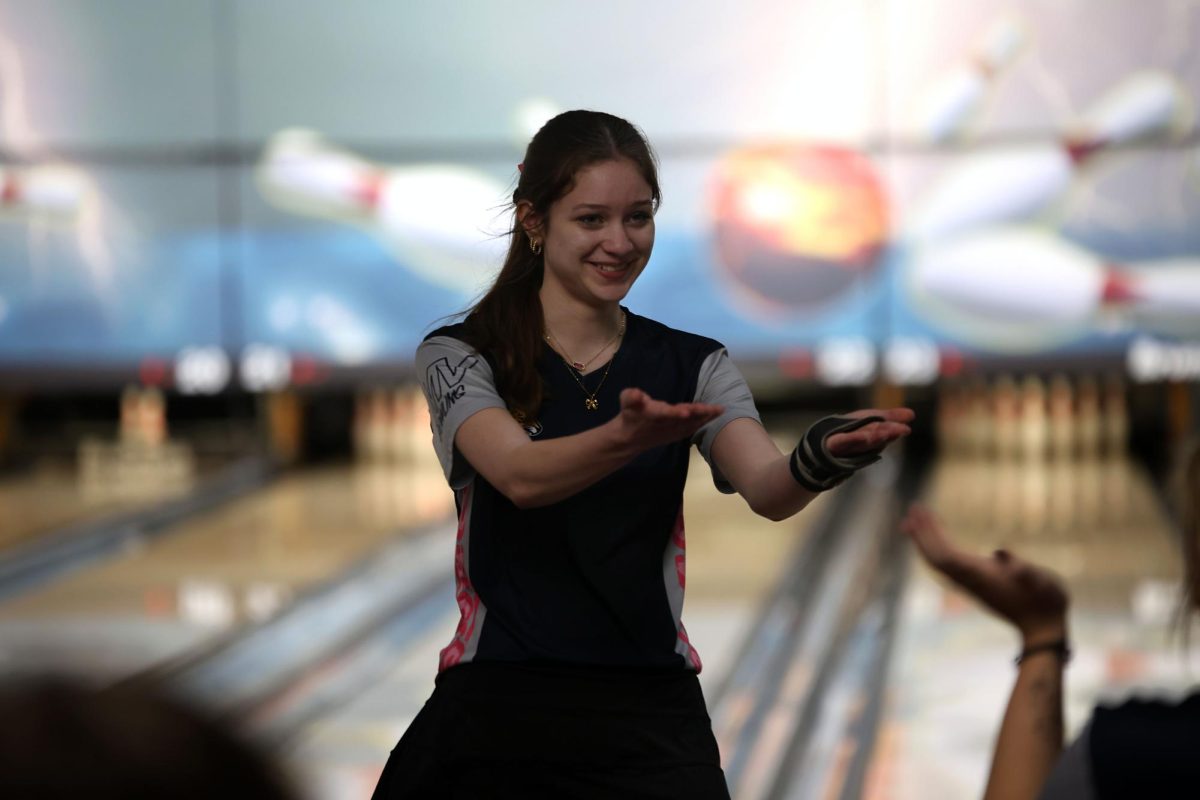 Smiling, junior Layla Gonzalez goes to low five her teammate after performing well. 