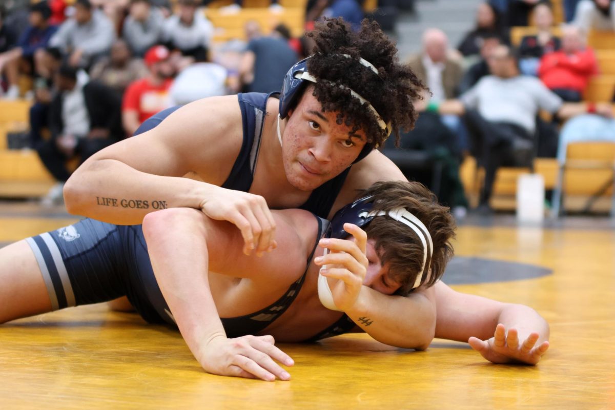 Pinning his opponent down, junior MJ Wash looks at his coaches.