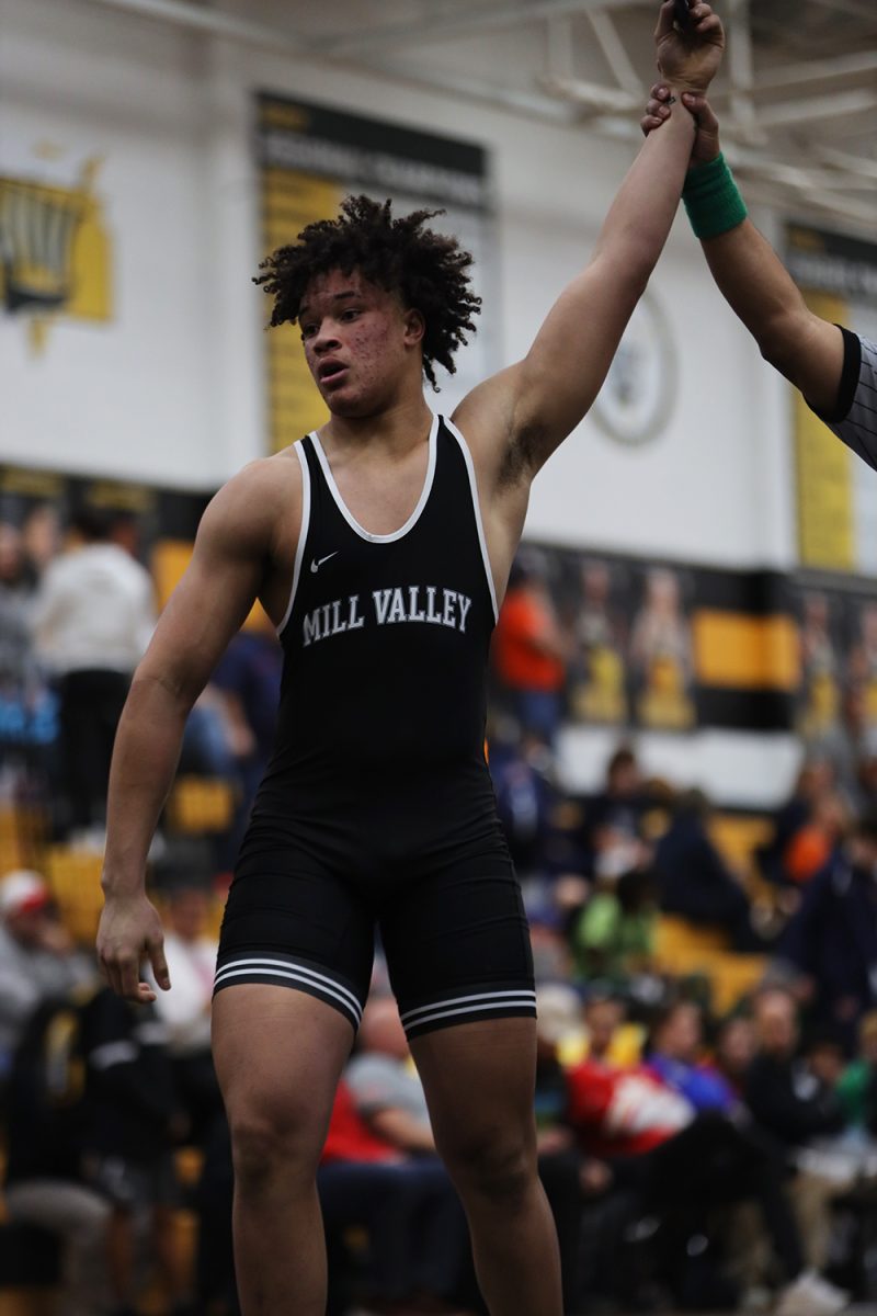 Looking away, junior MJ Wash gets his hand raised after winning his match.