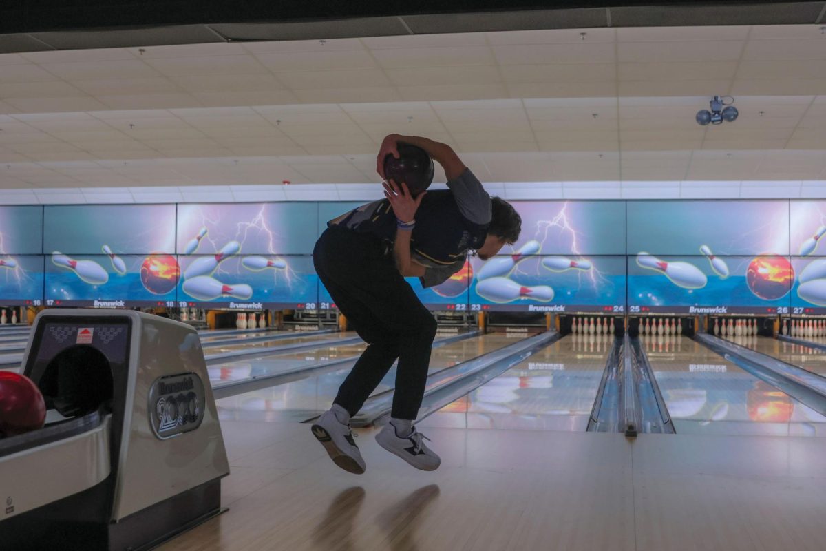 With his feet off the ground, junior Jake Brown approaches the lane to roll his ball. 