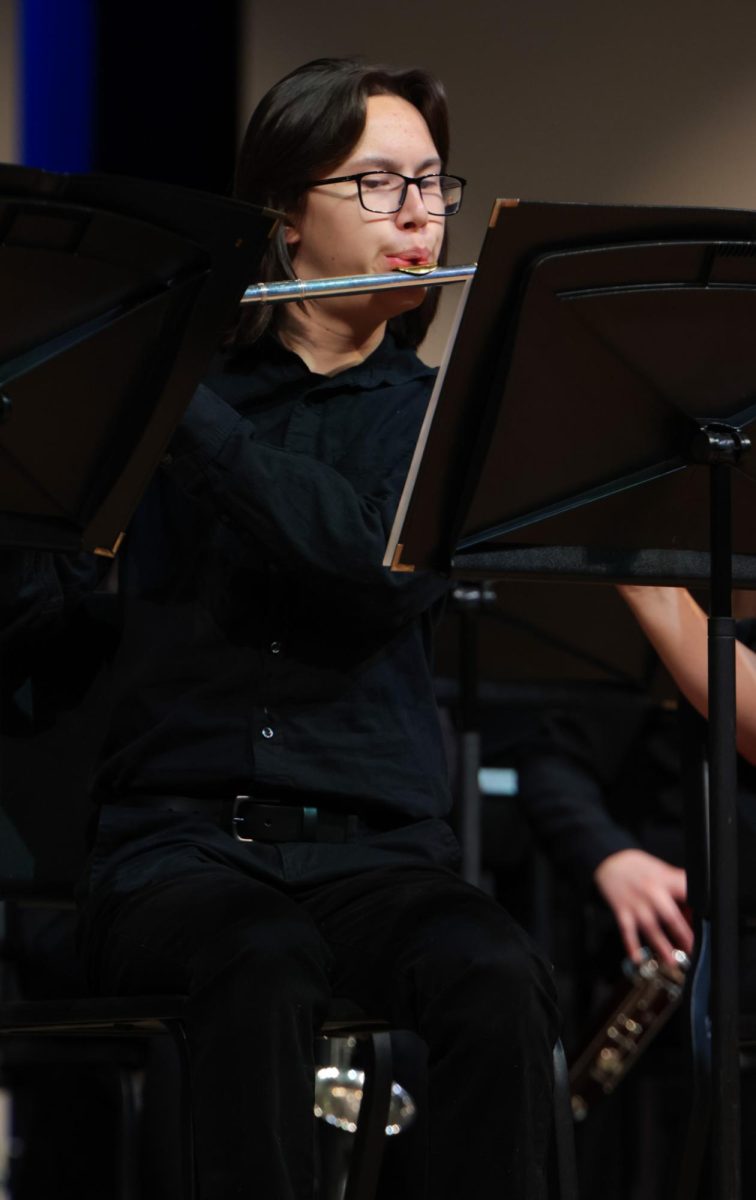 Raising his flute, freshman Calder Hsu hits the notes on his sheet music. 
