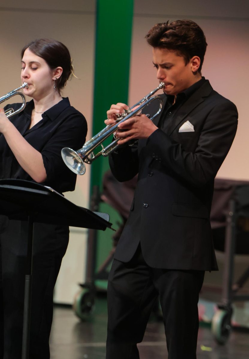 Looking at the music, sophomore Turner Bruce blows into his trumpet.
