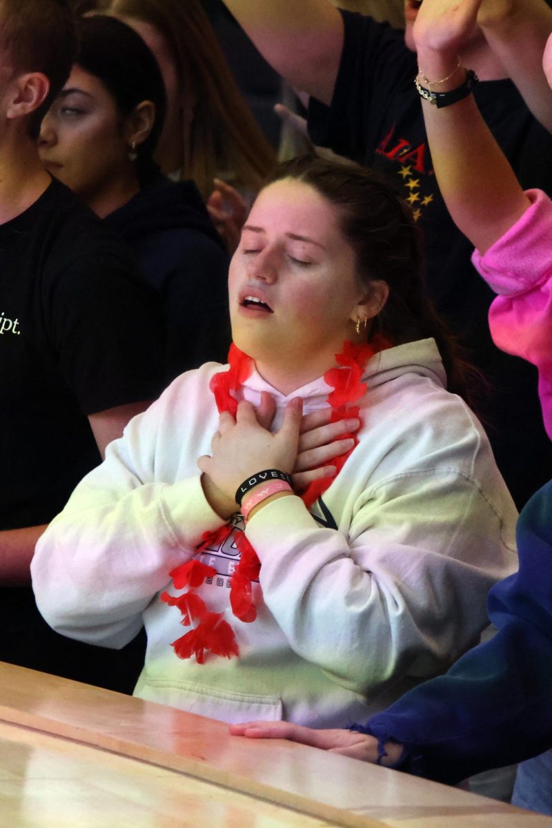 With her eyes closed, senior Maura Fleming places her hands over her heart.