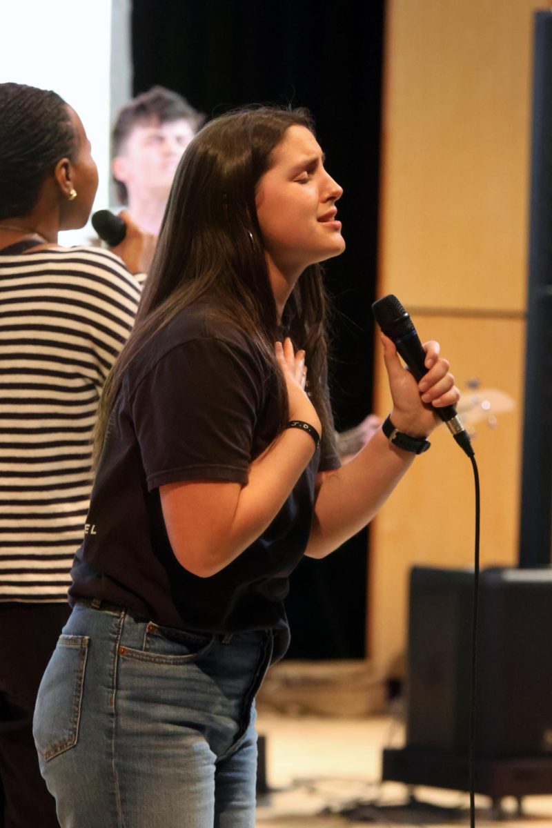 With a microphone in hand, sophomore Lacy Jennings sings a worship song.