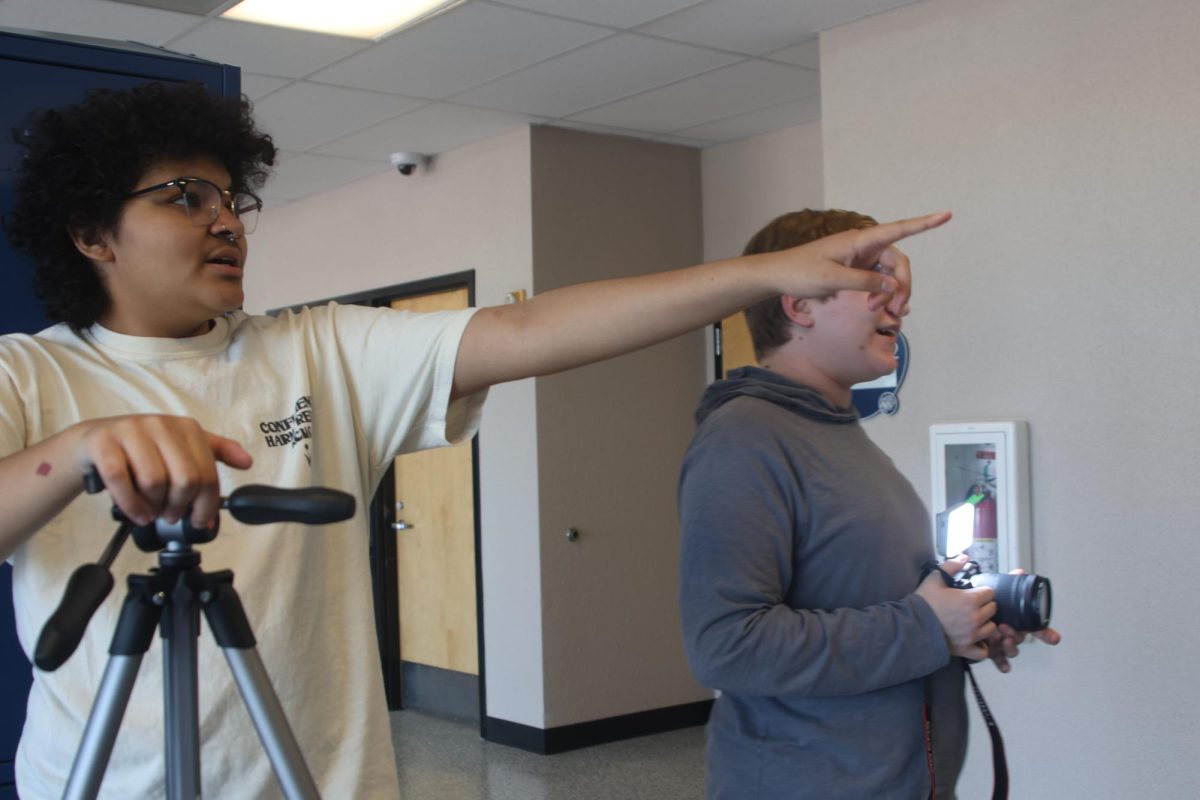 Pointing, junior Ellyott Edwards gives directions to the students acting in the film.  