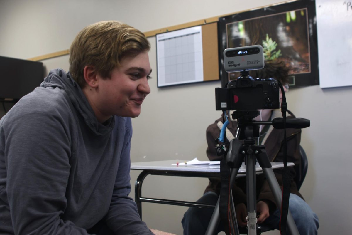 Smiling, junior Evan LeRoy watches back what he has just filmed. 