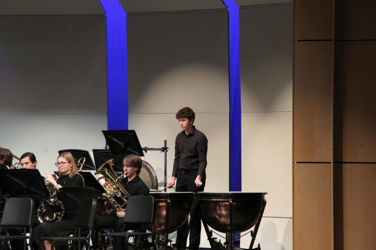 Playing the drums, junior Nathan Turvey watches the conductor for his cue.  