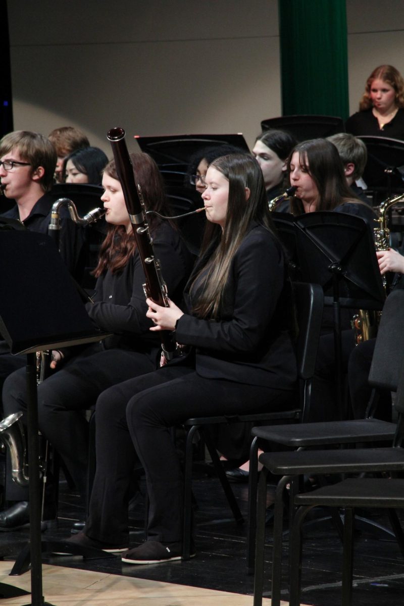 Raising her French horn, senior Marissa Akehurst looks at her music. 
